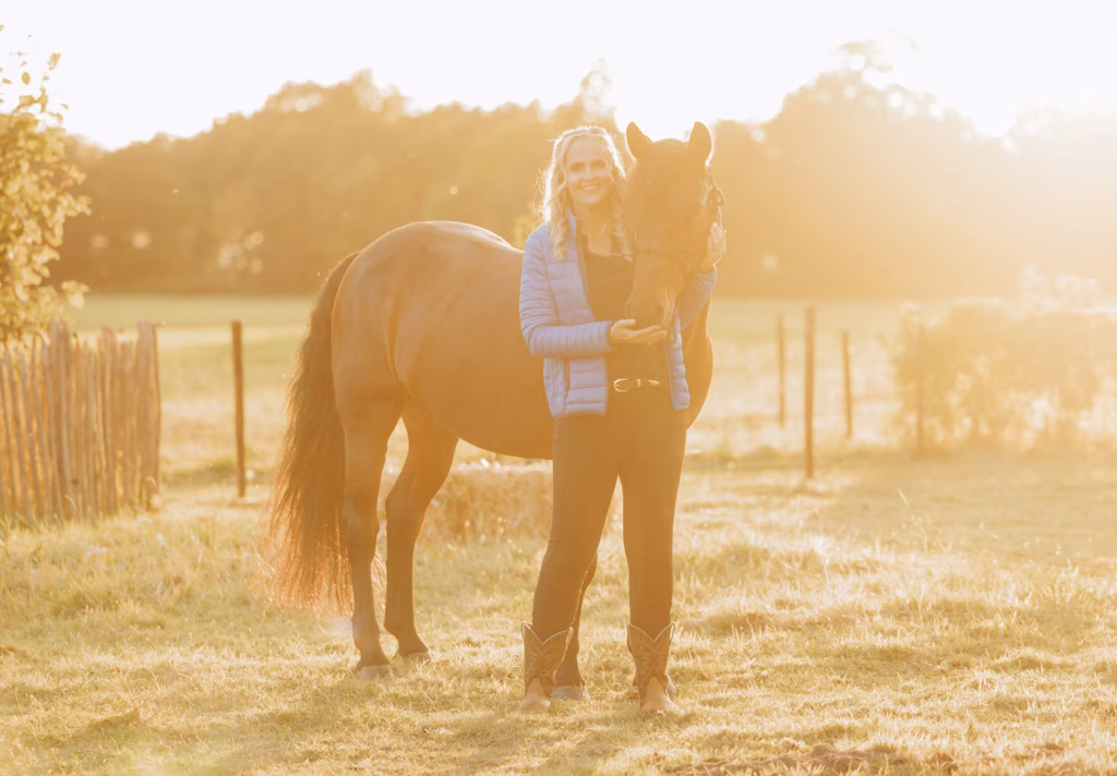 Persoon met bruin paard in zonnig weiland